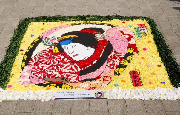 Mural colorido de flores que representa a una mujer con kimono en un fondo amarillo.